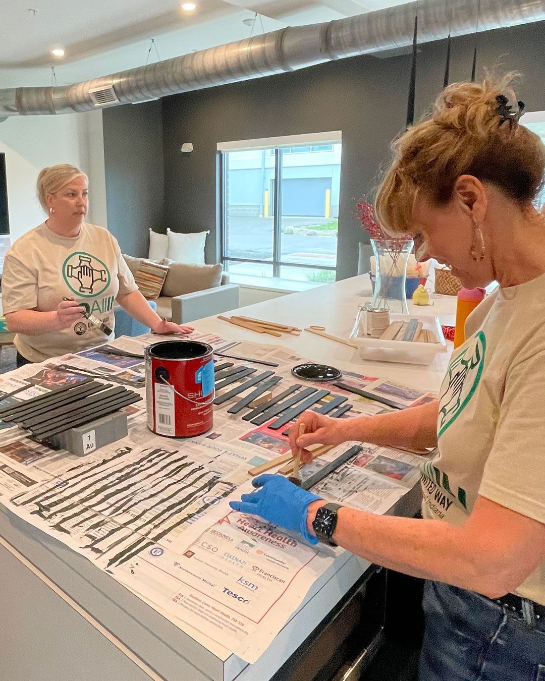 Volunteers from UWCI paint bases for bead curtains at the FRC.