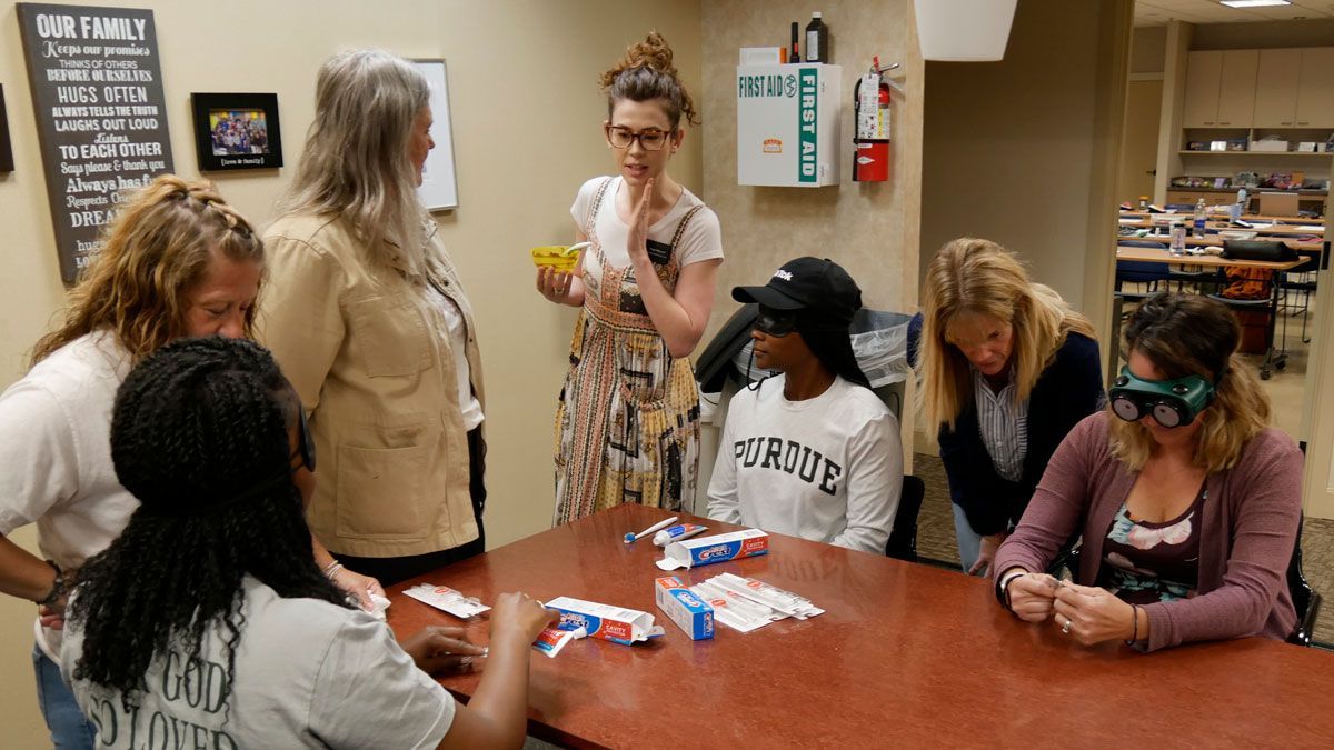 Participants sit around a table in the kitchen at VIPS and train wearing blindfolds and simulation goggles.