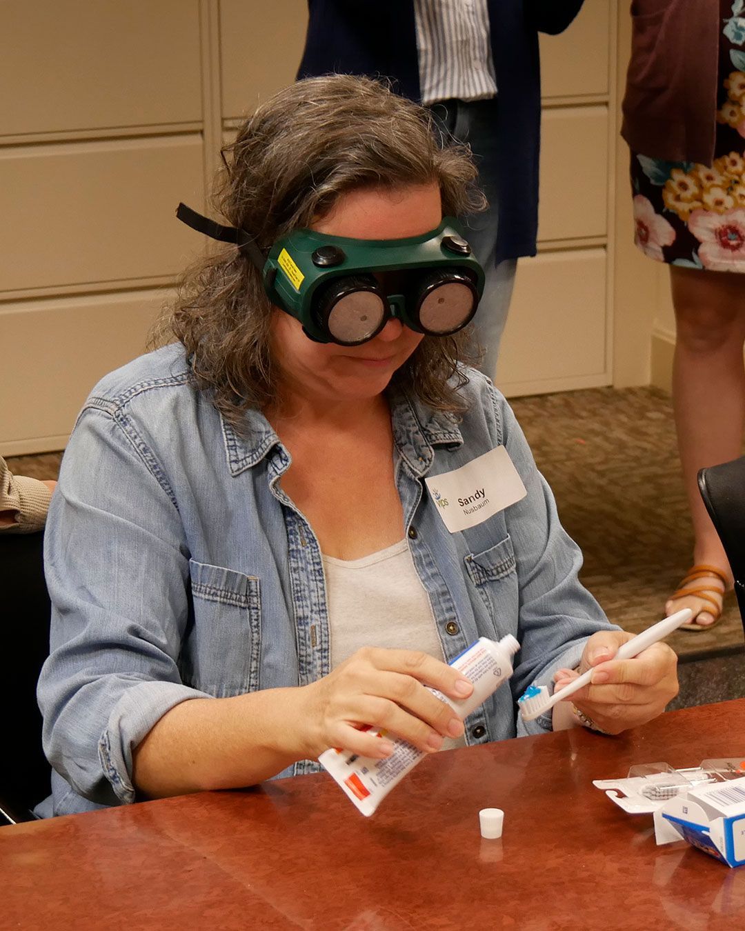 A participant attempts to put toothpaste on a toothbrush while wearing simulation goggles.