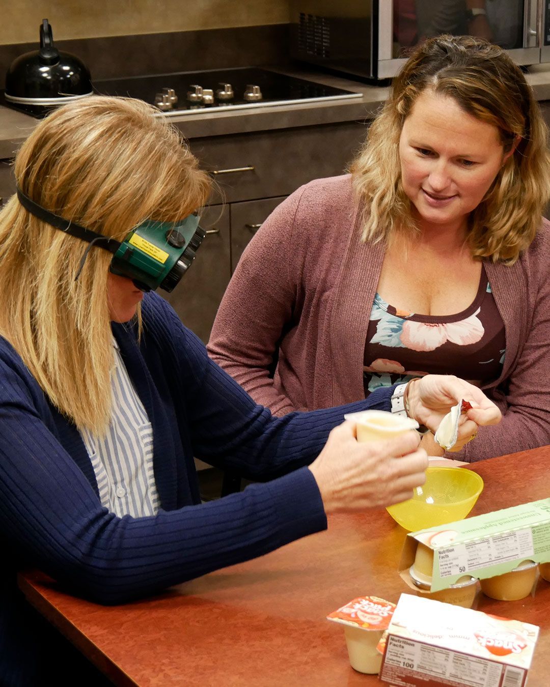 A participant attempts to open a pudding package while wearing simulation goggles.