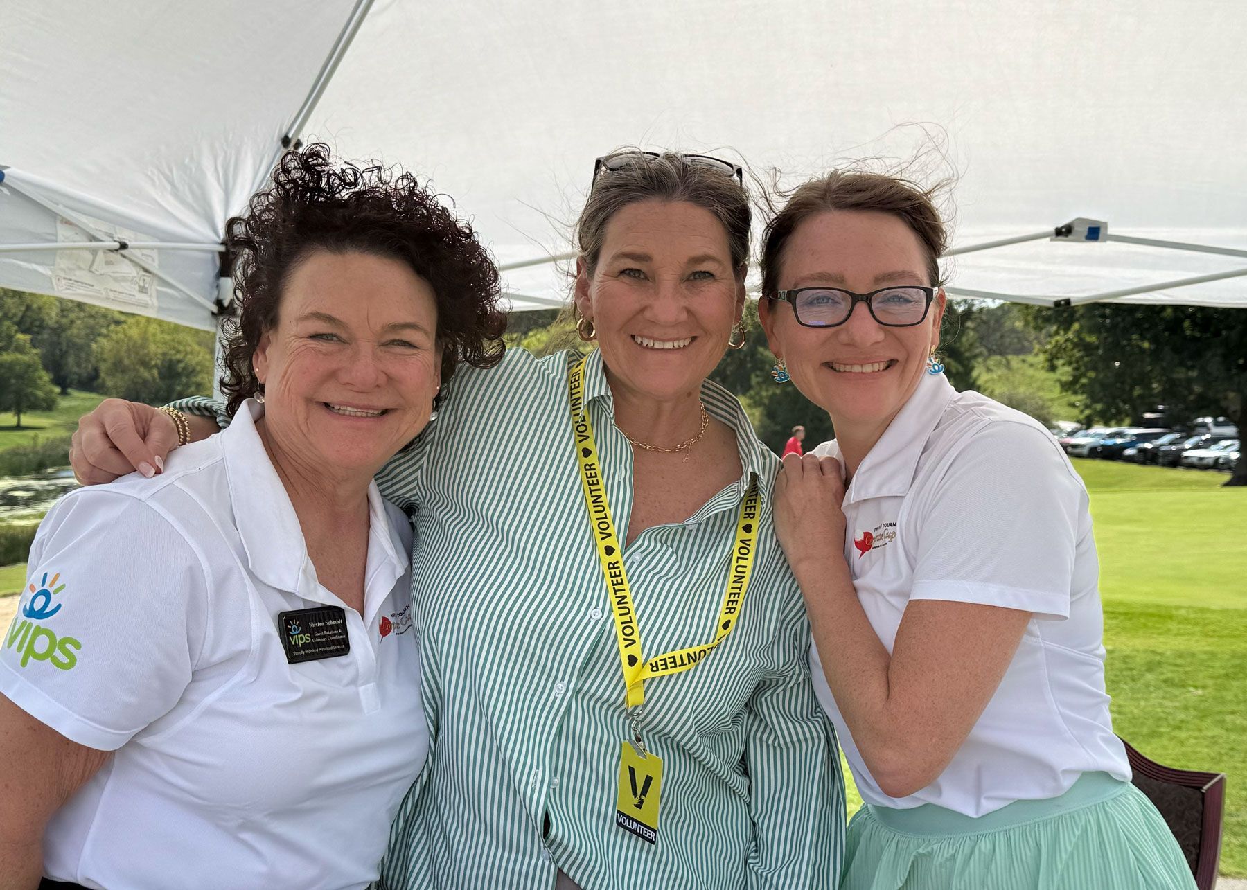 Kirsten Schmidt, Kelly Easton, and Christina Welsh pose for a phot under the Cannonball Experience tent.