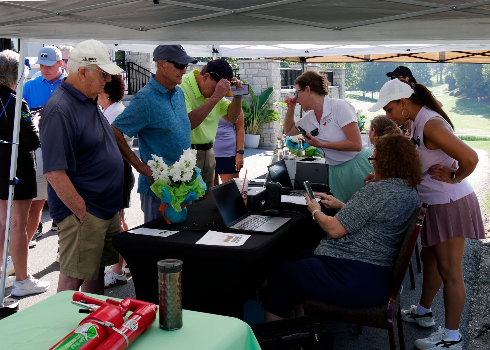 VIPS staff sitting at a table signing in golfers. Golfers are standing on the other side wait to register.