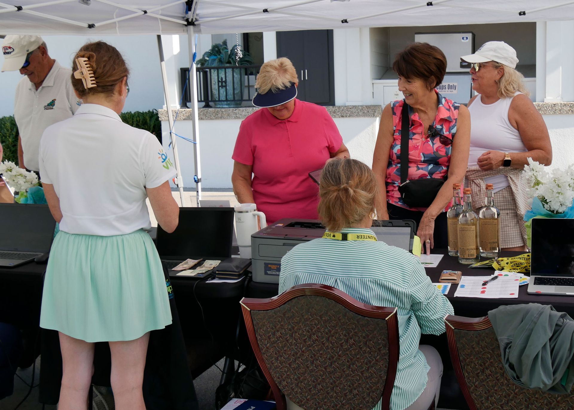 VIPS staff sitting at a table signing in golfers. Golfers are standing on the other side wait to register.