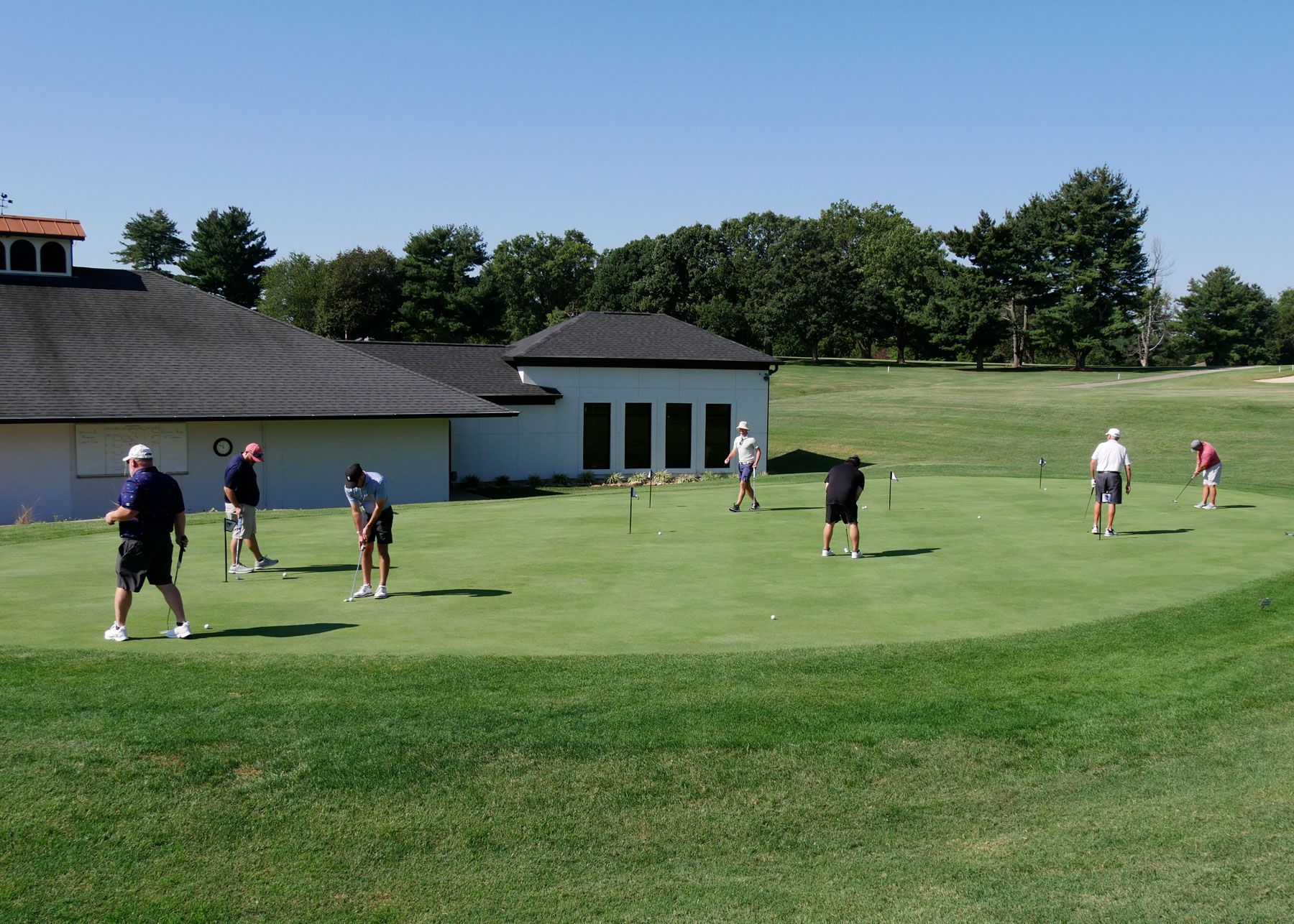 A group of men practice putting before the golf scramble begins.