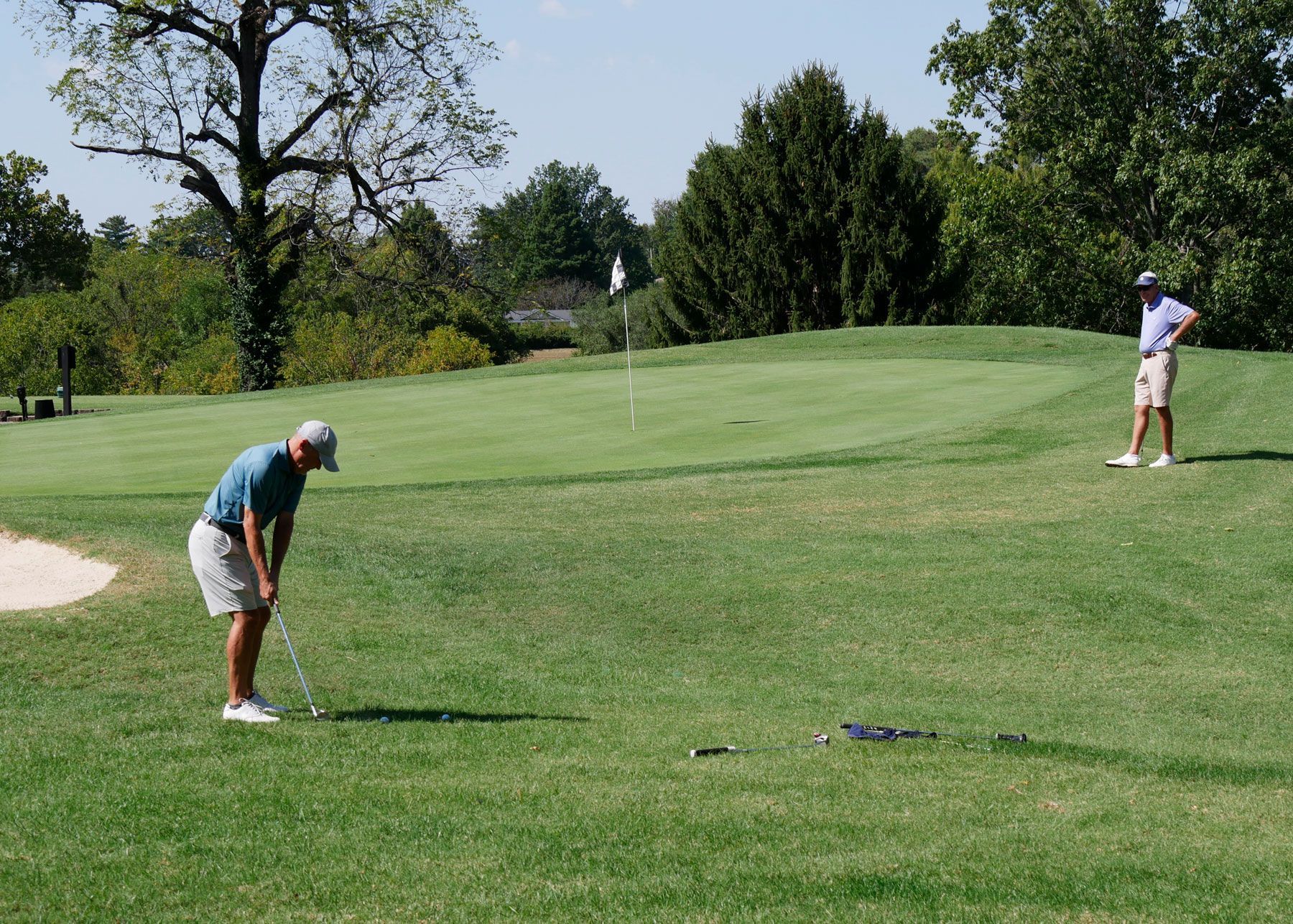 A man chipping while his team member watches.
