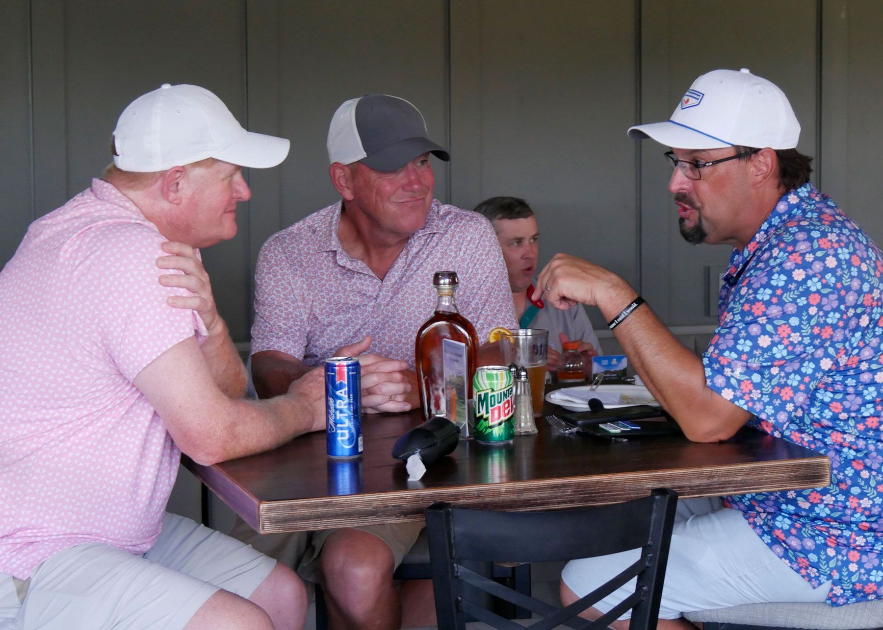 Doug Voss chats with two of his teammates sitting at at table in the clubhouse after the scramble.