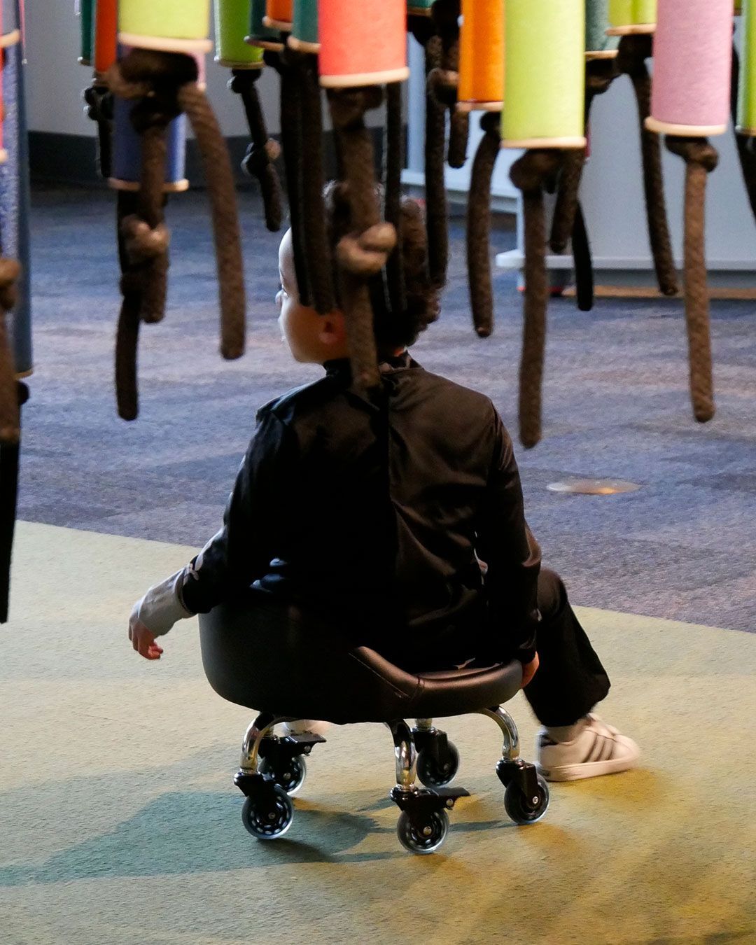 A small boy rolls under the pool noodles hanging from the ceiling at the Kentucky Science Center.