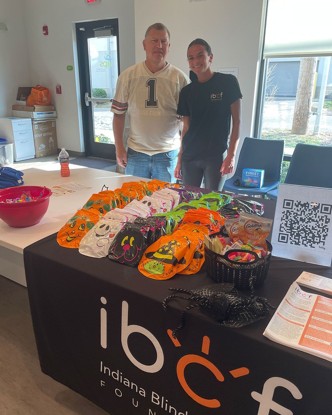 A man and woman representing Indiana Blind Children's Foundation pose for a photo behind their display table at the FRC.