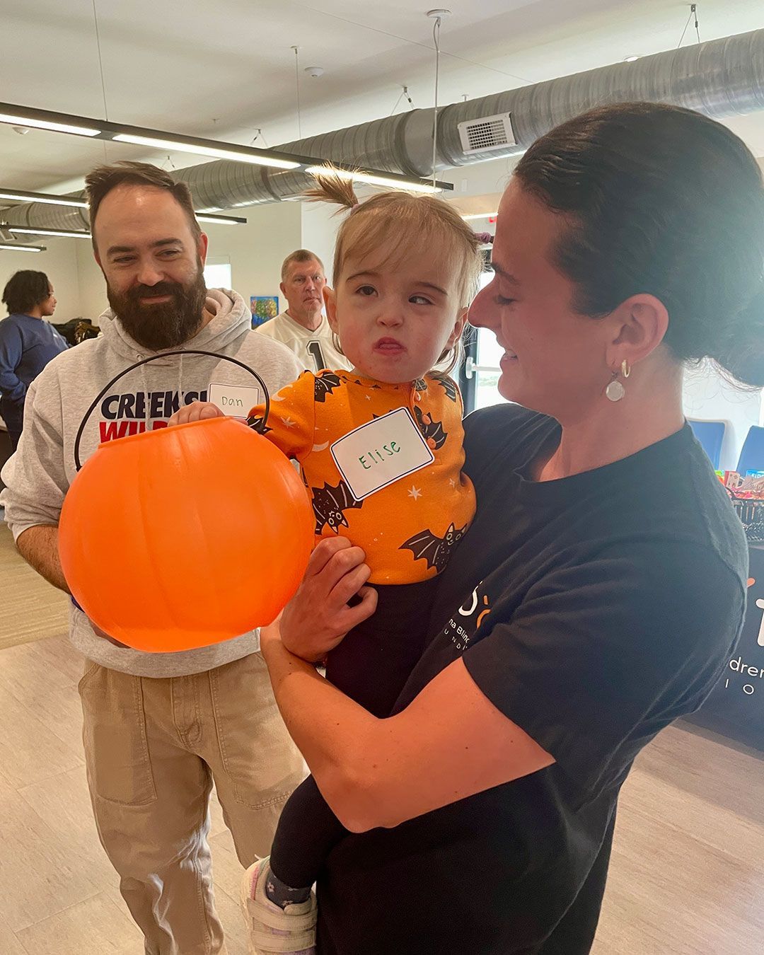 A small girl with a Jack O'Lantern is held by a woman from the Indiana Blind Children's Foundation.