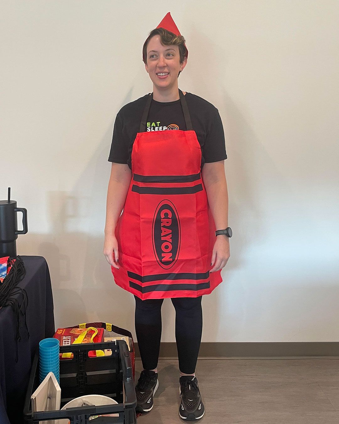 A woman dressed as a red crayon poses for a photo.