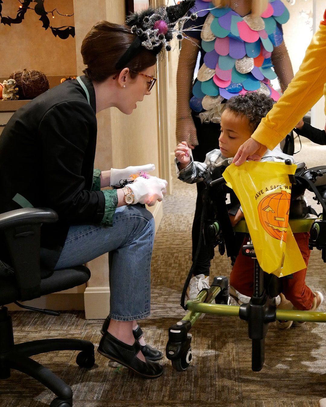A small boy in a mobility chair gets a treat from Miss Paige.