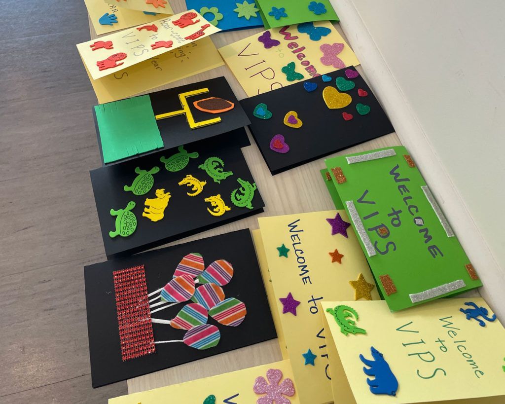 'Welcome to VIPS' cards made by volunteers from the NCAA PR team are displayed on a table.