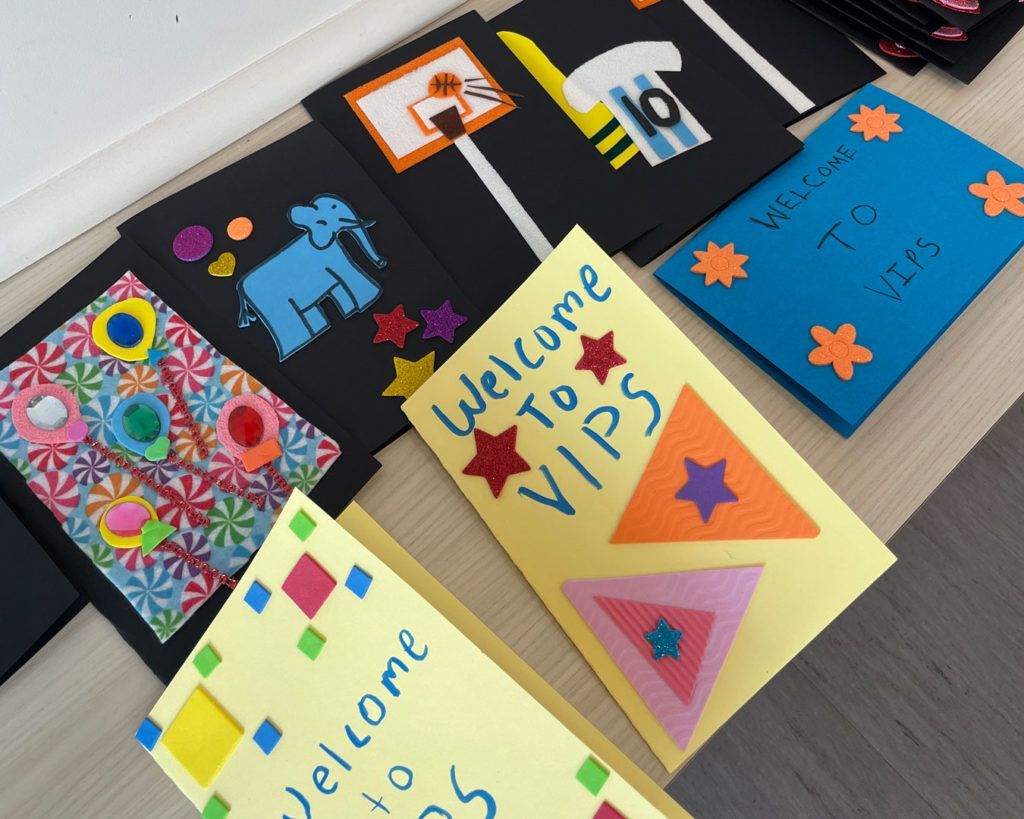 'Welcome to VIPS' cards made by volunteers from the NCAA PR team are displayed on a table.