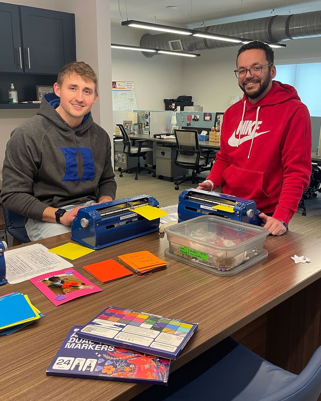 Two volunteers from Mercy Road Church make braille inserts for cards at the Family Resource Center.