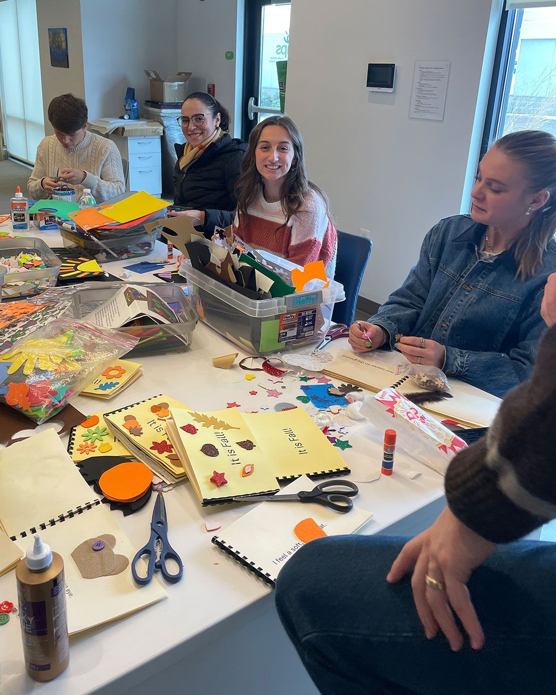 Volunteers from Mercy Road Church sit at the work table in the Family Resource Center and make sensory books.