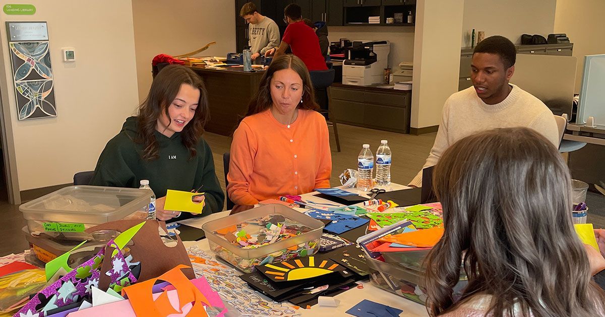 Volunteers from Mercy Road Church sit at the work table in the Family Resource Center and make cards
