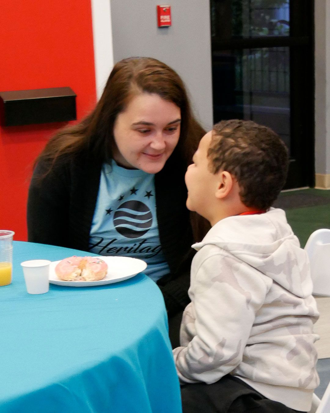 A mother and son share a smile and a donut.