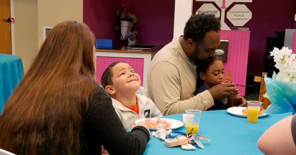 Parents sit with their children while enjoying juice and donuts.