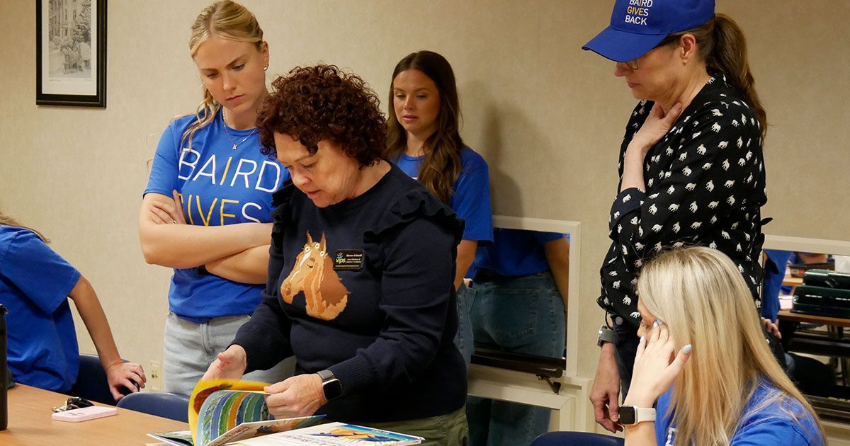 Kirsten shows the volunteers where to place the braille translations into the books.
