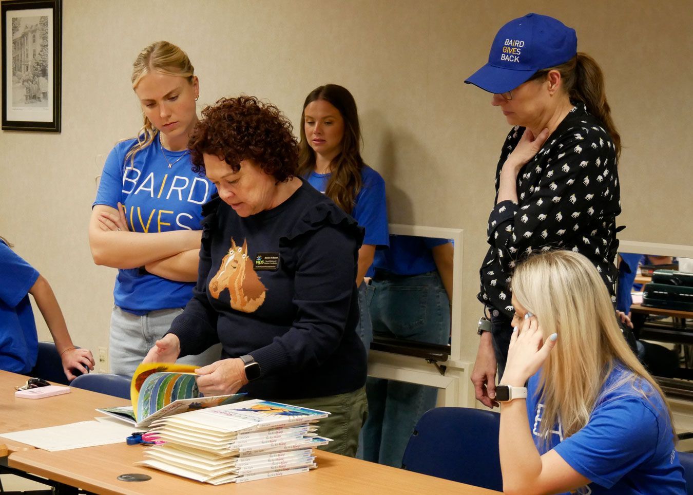 Kirsten shows the volunteers where to place the braille translations into the books.