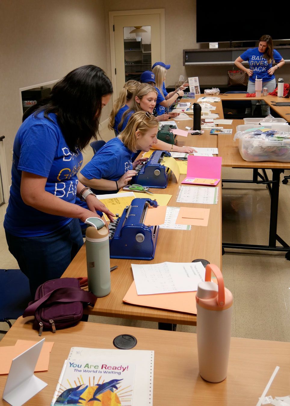 Baird volunteers use the braillers to make card inserts.