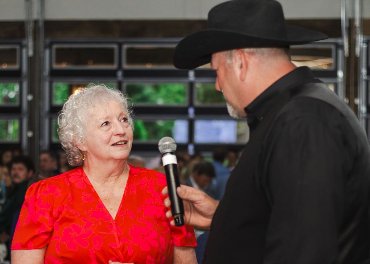 The golden ticket raffle winner stands and talks to the auctioneer.