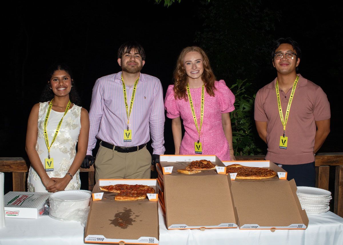 UofL student volunteers pose for a photo while handing out pizza and donuts.