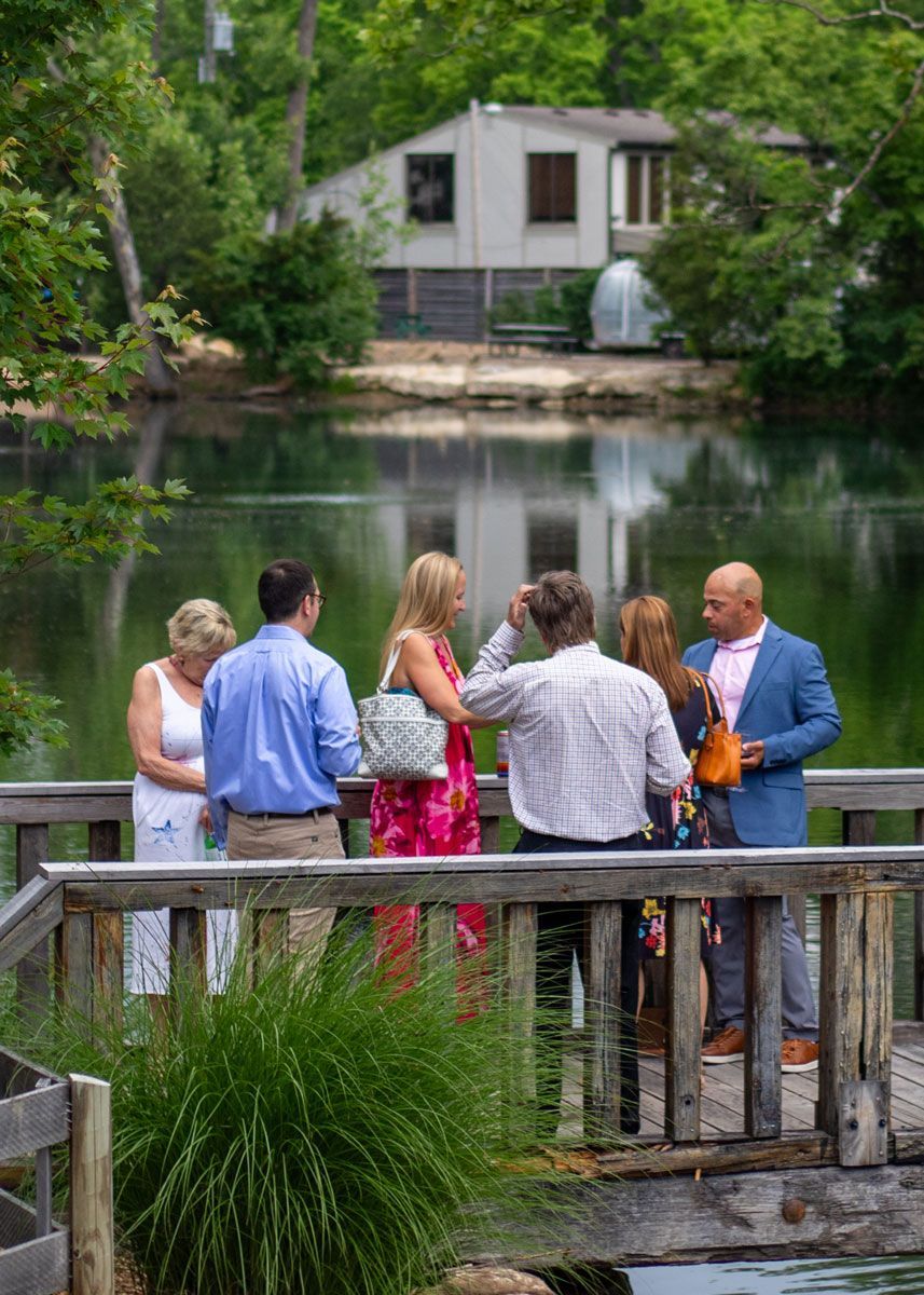 Gala attendees hang out on a bridge spanning a pond at Progress Park.