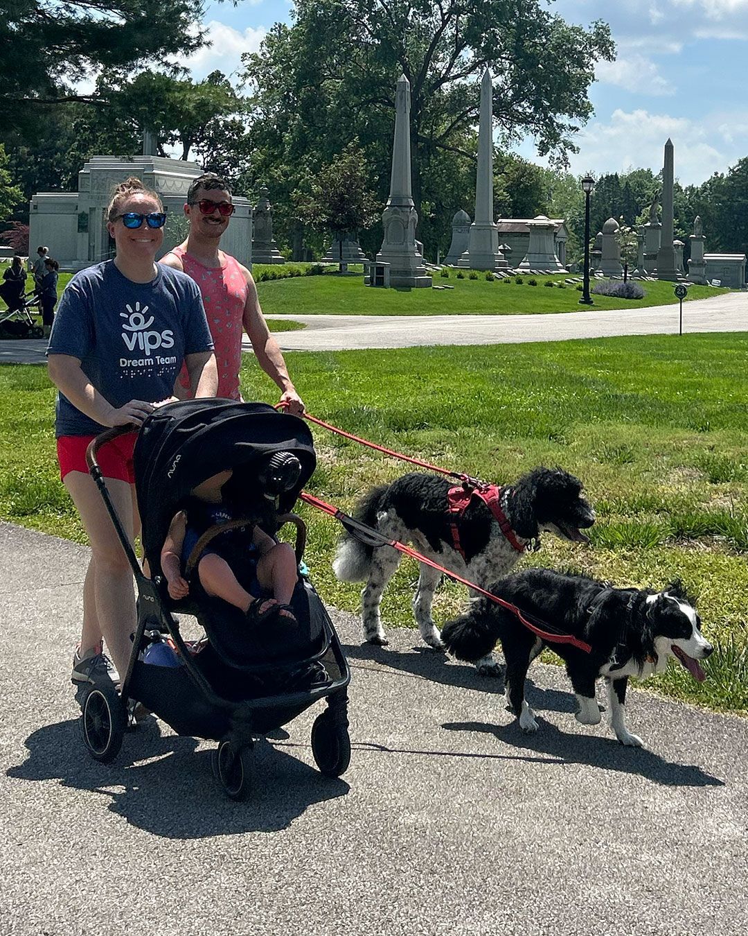 A family pushing a stroller with two dogs on a leash during Walking for Dreams.