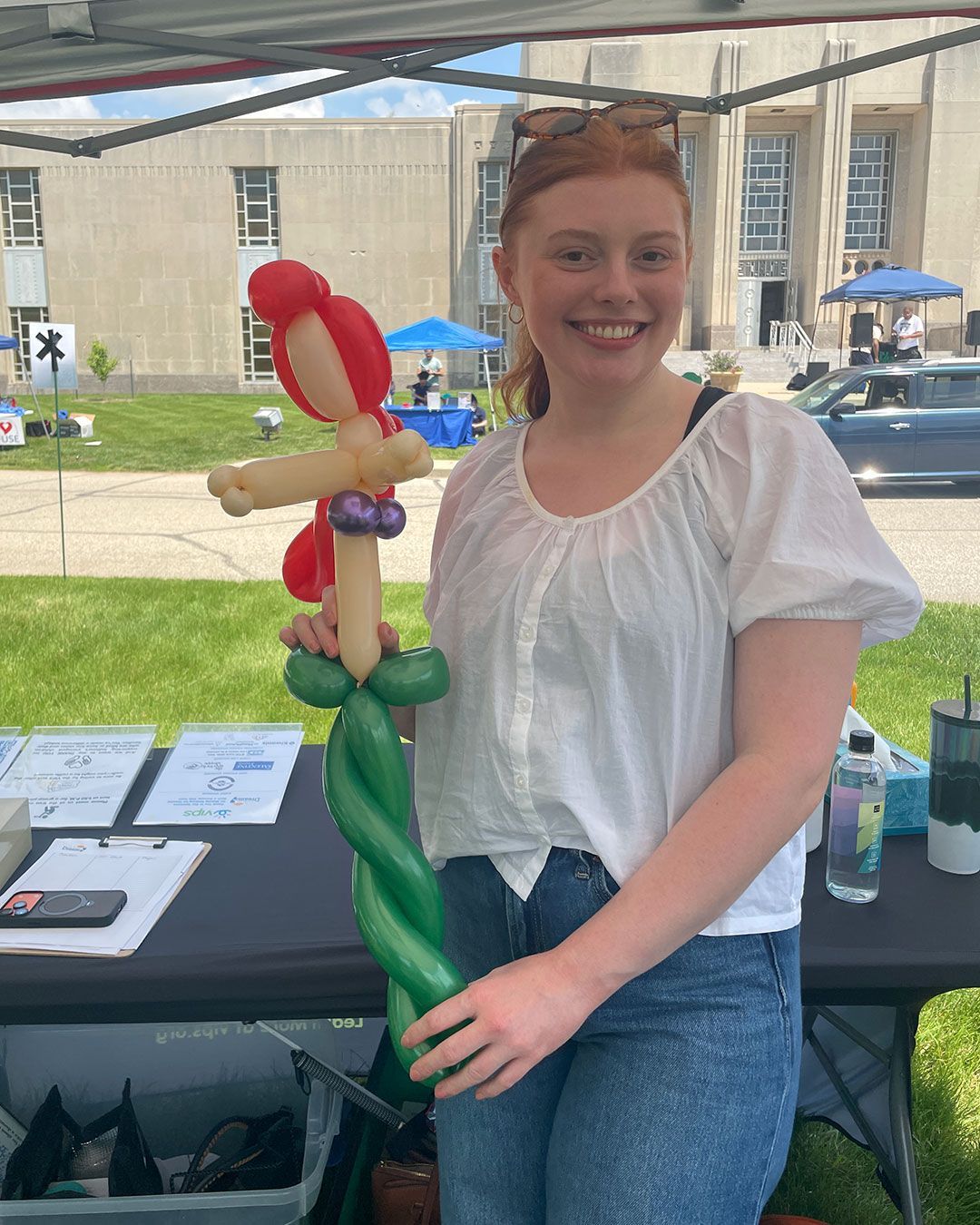 Caitlyn poses for a photo behind the registration table while holding a balloon animal.