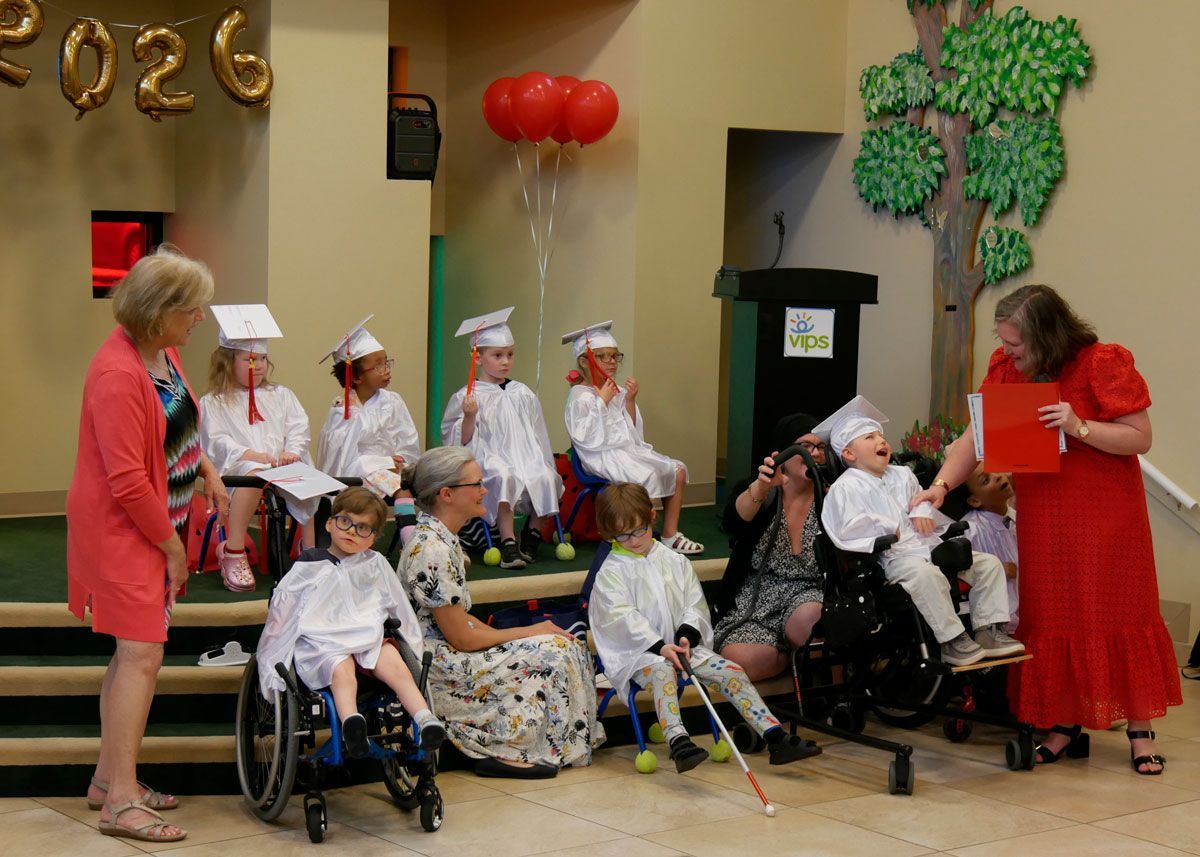 Miss Staci hands out diplomas to the Red Room graduates on the stage in Kids Town.