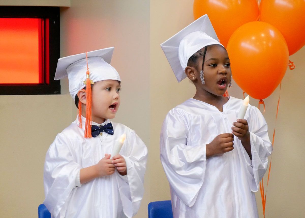 Graduates hold electric candles and sing 'This Little Light of Mine.'