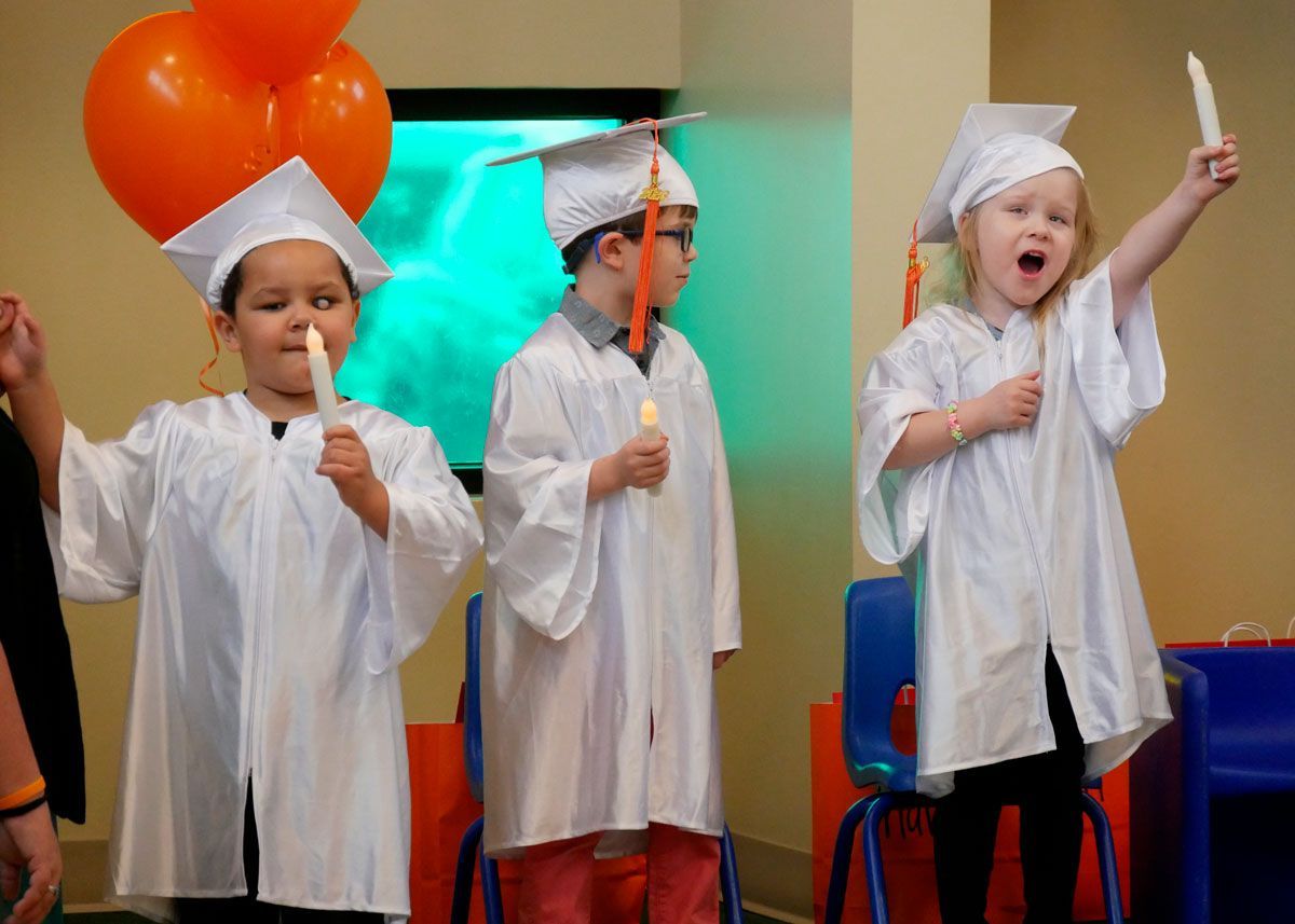 Graduates hold electric candles and sing 'This Little Light of Mine.'