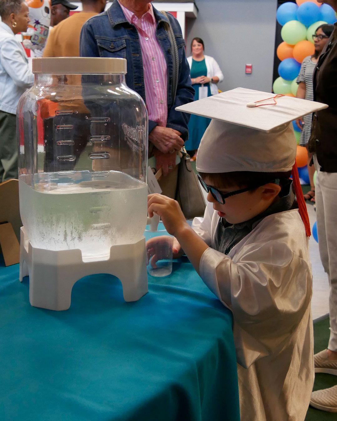 A graduate fills his cup at the refreshment table.