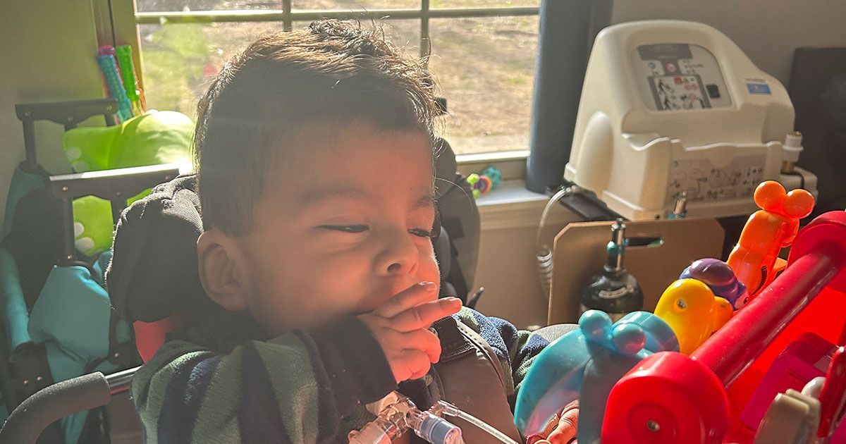 Angelito sits in a chair and plays with an interactive toy.