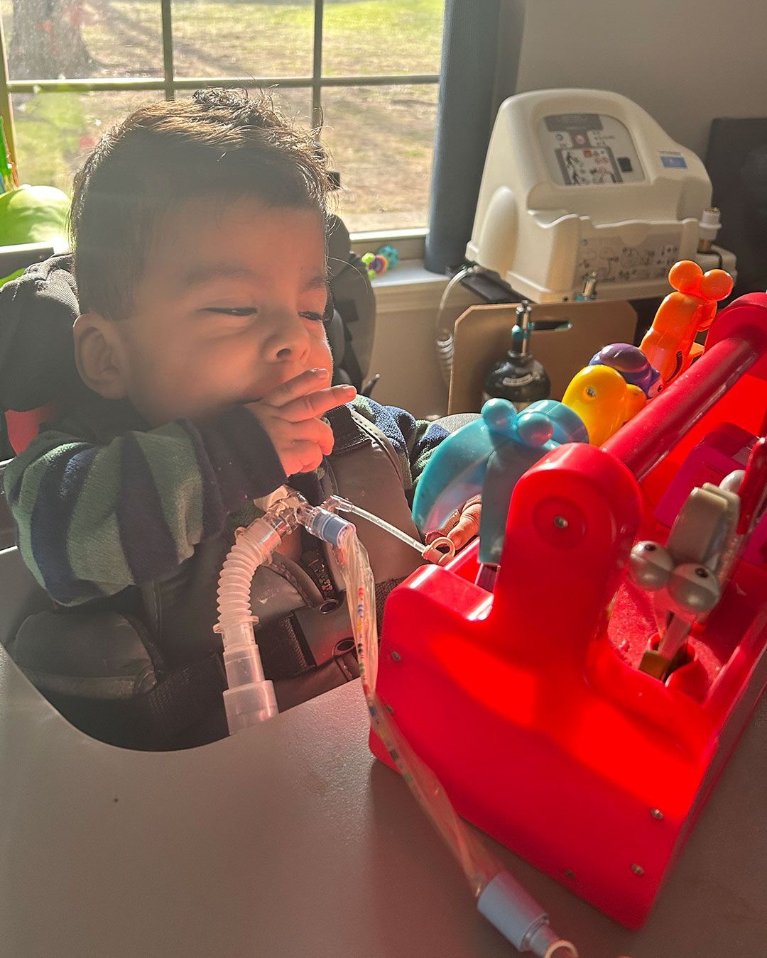 Angelito sits in a chair and plays with an interactive toy.