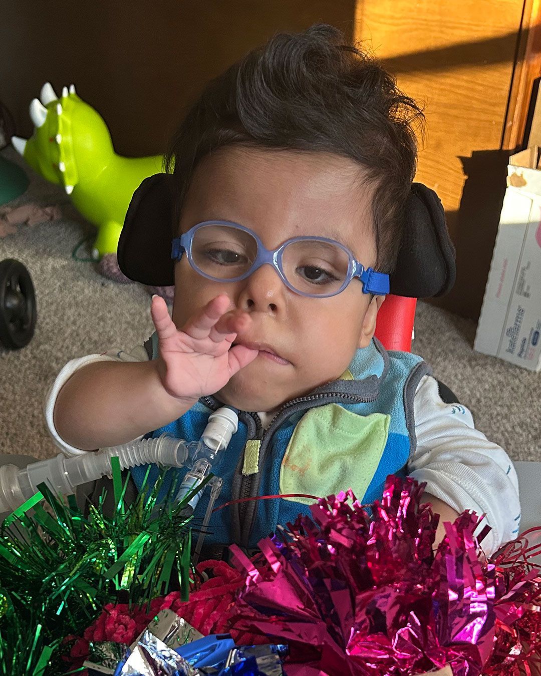 Angelito is sitting in a chair and is surrounded by colorful bows and streamers.