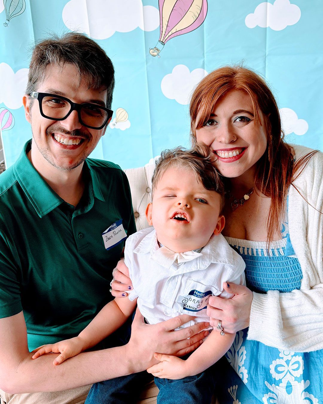 Sonny sits between his parents, Zach and Kacey, and they are smiling and posing for a photo.
