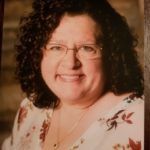 Woman with glasses smiling at the camera.