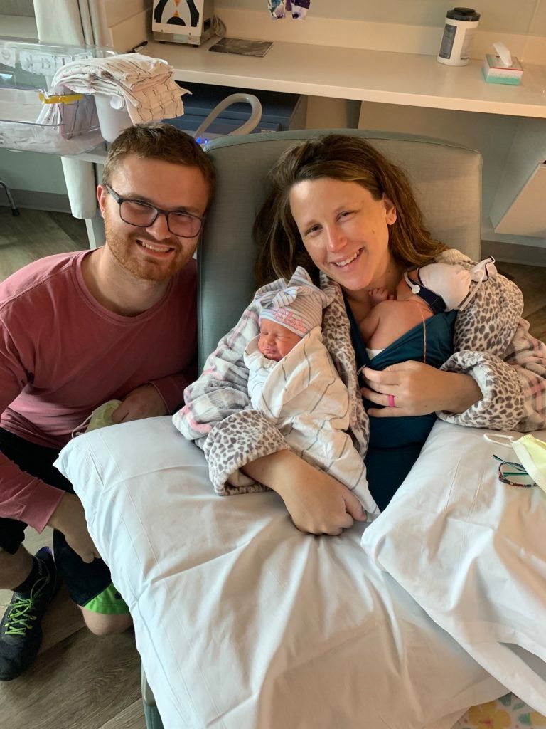 Parents hold their twin daughters in a hospital room