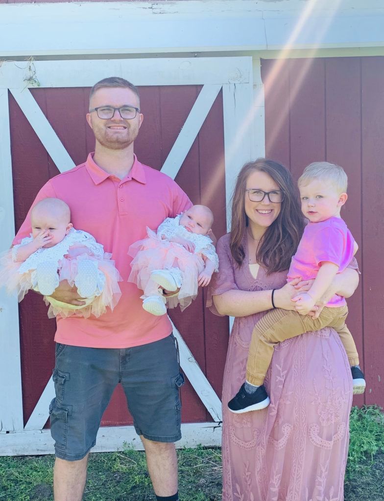 Father holding twin infant girls and mother holding a young boy