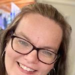 Woman with glasses smiling at the camera.