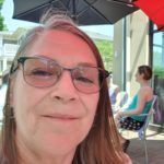 Woman with glasses has a slight smile for the camera.