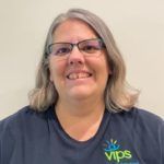 Woman with glasses smiling at the camera.