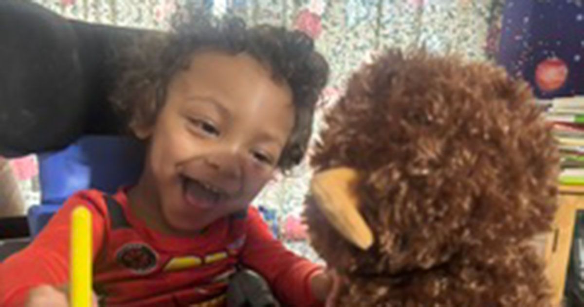 Dallas is smiling and playing with his switch-activated plushie toy.