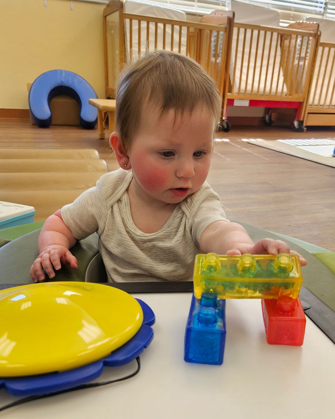 Eleanor is reaching for and grabbing large building blocks.