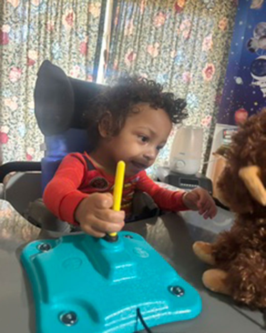 Dallas is smiling, sitting, and playing with toys.