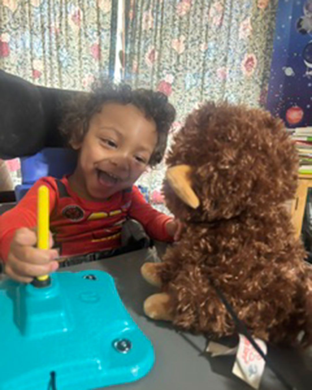 Dallas is smiling, sitting, and playing with toys.
