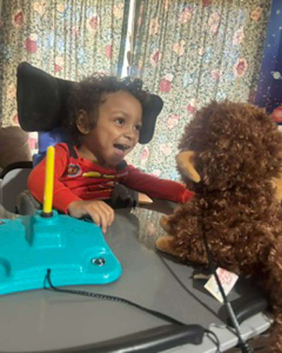 Dallas is smiling, sitting, and playing with toys.