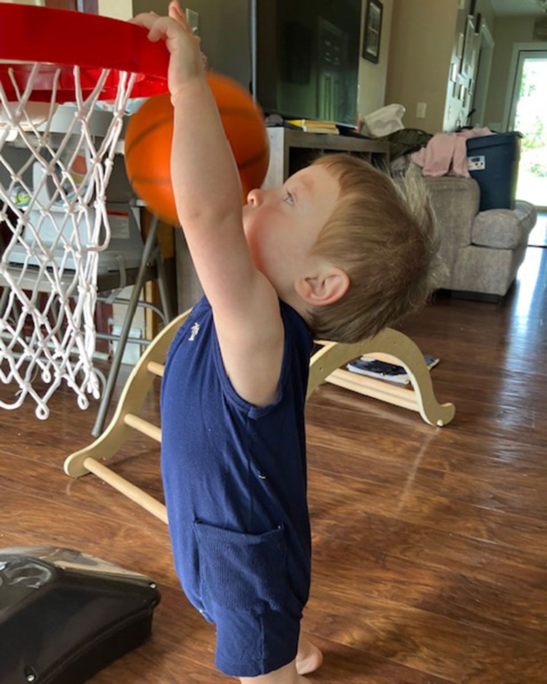 Luke is dunking a basketball in a hoop set up in his living room.